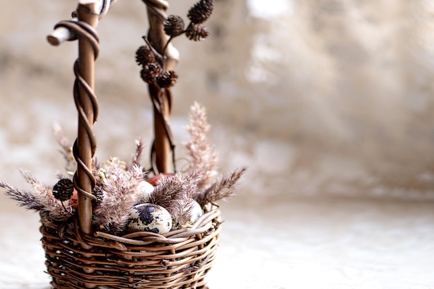 Easter composition with small eggs and dry fluffy grass in wicker basket