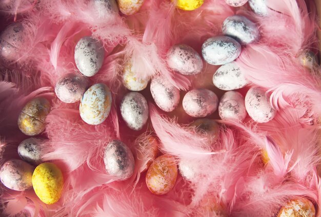 Easter composition with traditional decor of small colored eggs and soft feathers.
