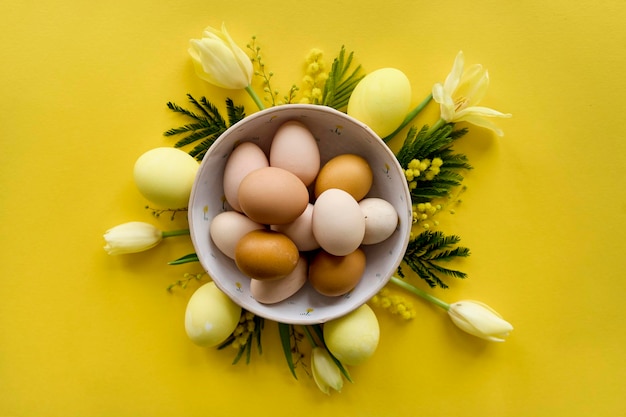 Easter composition of yellow tulips eggs and cookies on a yellow background