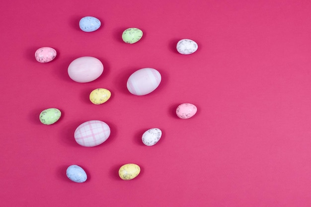 Easter concept Easter multicolored eggs near a basket with white flowers on a red table on a background of a white wall Place for an inscription For greeting cards