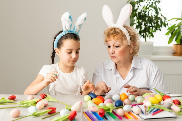 Easter concept. Grandmother with granddaughter are holding Easter eggs at home.