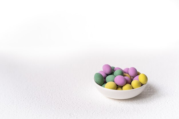 Easter concept. Mini eggs in little plate on white background. Color eggs pattern, easter background.