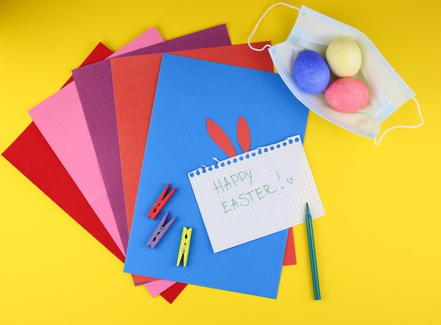 Photo easter concept with coloured papers, eggs and medical masks