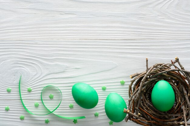 Photo easter concept with green eggs in the nest on wooden table.