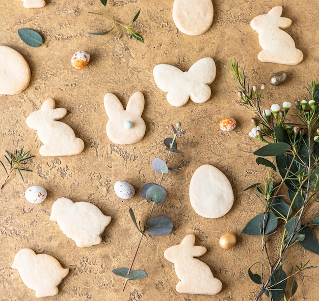 Biscotti pasquali con uova a forma di caramelle su un piatto di ceramica e decorazioni floreali concetto di vacanza