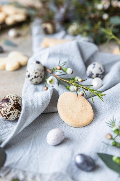 Easter cookies with candies shaped eggs floral decor and quail eggs on linen napkin Holiday concept