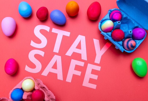 Photo easter at coronavirus days stay safe text message and easter eggs on red orange color background top view