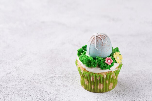 Easter cupcakes with mastic eggs and grass on table. Easter holiday concept. Copy space