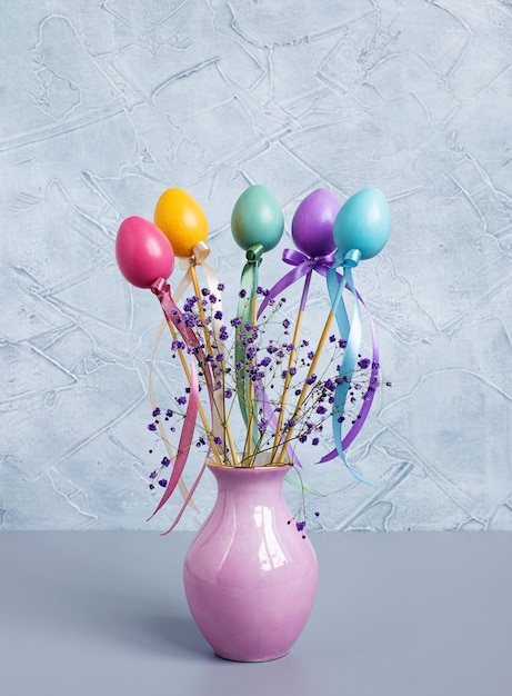 Photo easter decor colorful eggs with ribbons and bows in a pink vase vertical photography