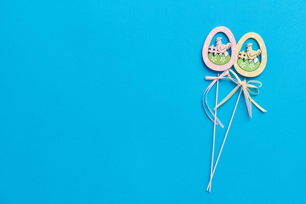 Easter decor in the form of wooden eggs on a stick on a blue background