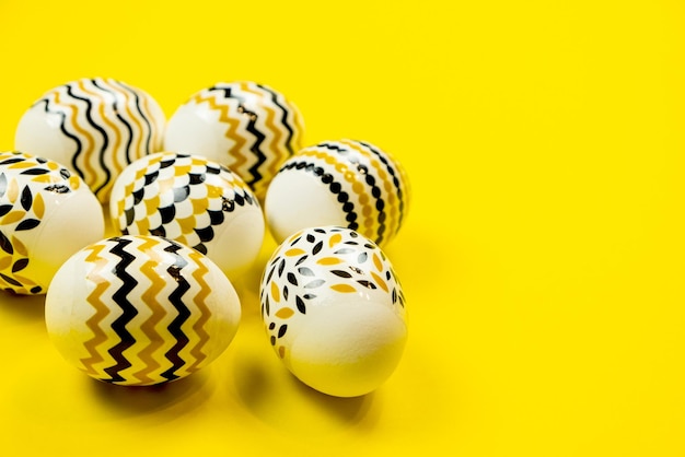 Easter decorated eggs in black and yellow stripes and a dot on a yellow background Minimal Easter concept Flat lay of trendy easter eggs