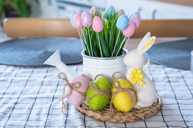 Easter decoration of colorful eggs in a basket and a rabbit on the kitchen table in a rustic style Festive interior of a country house