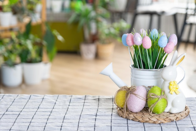 Easter decoration of colorful eggs in a basket and a rabbit on the kitchen table in a rustic style Festive interior of a country house