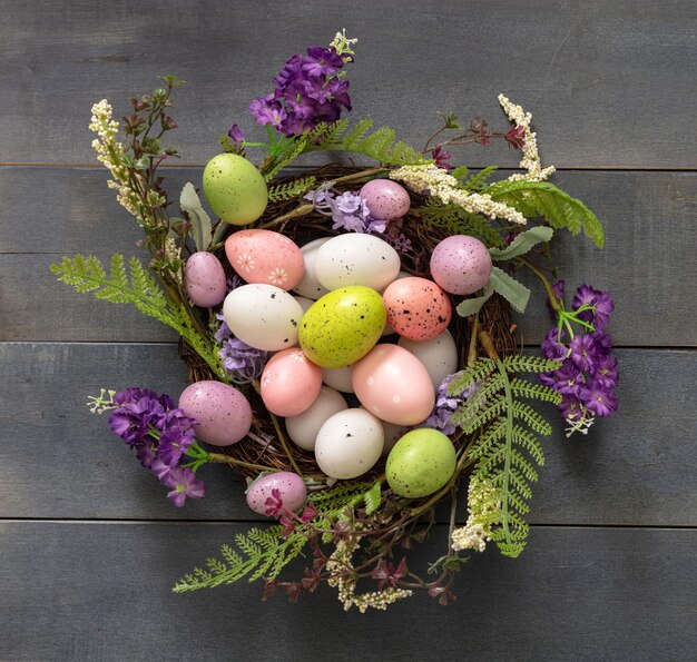 Easter decoration egg nest on blue wood Festive flower wreath full of pastel color egg