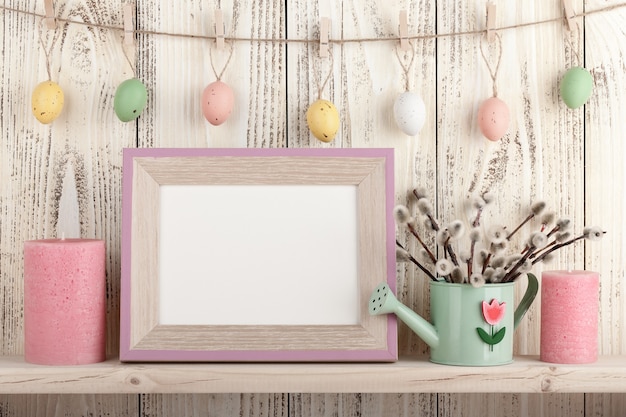 Easter decoration with blank wooden frame on the shelf