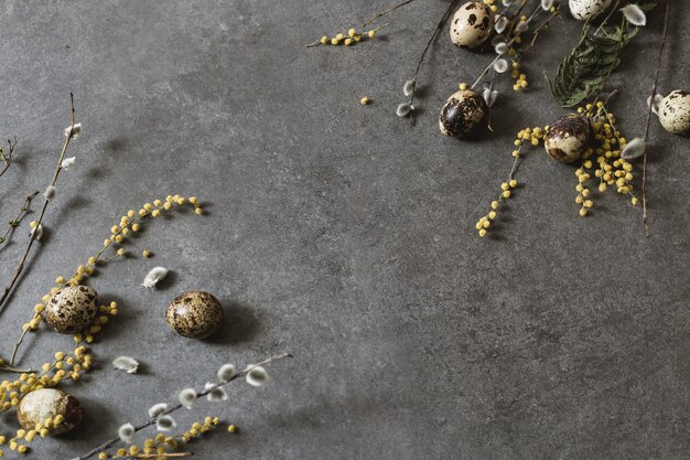 Decorazione di pasqua con uova di pasqua e fiori primaverili. uova gialle su grigio