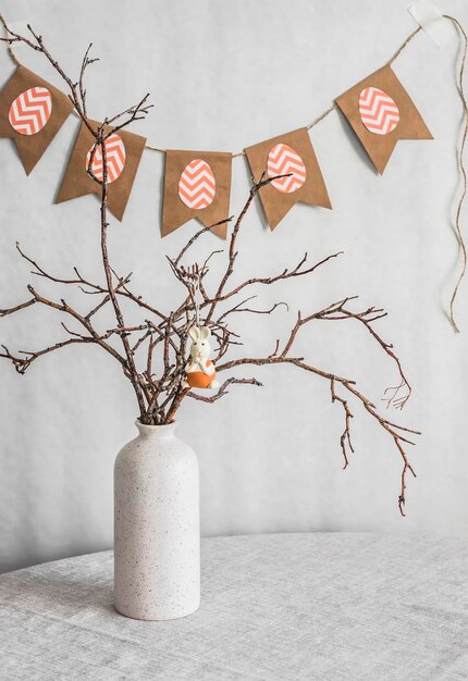 Easter decorations home still life vase with branches and paper garland on a light background