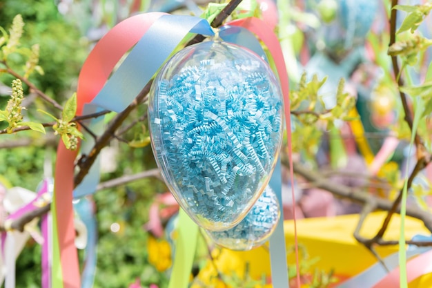 Пасхальные декоративные яйца и красочные ленты на ветвях деревьев