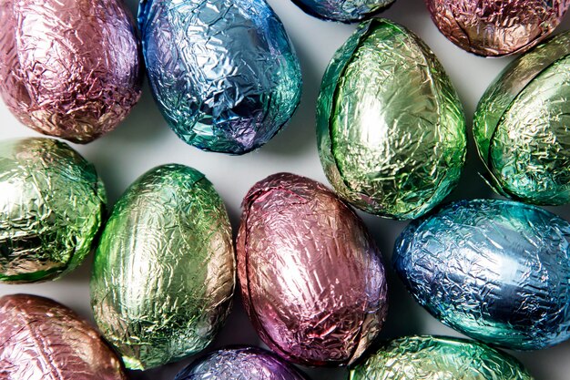 Easter egg chocolate treats wrapprd in shiny coloured foil on a marble background