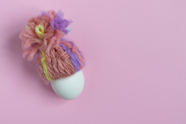 Easter egg in a hat on a lilac background with a place for text Holiday