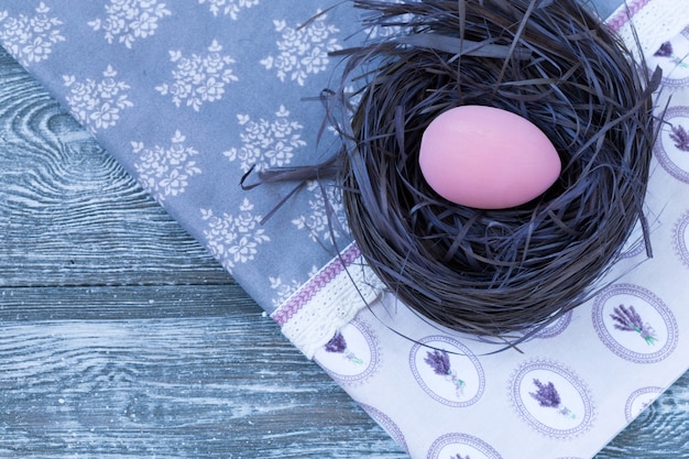 Uovo di pasqua in un nido, tovagliolo su un legno