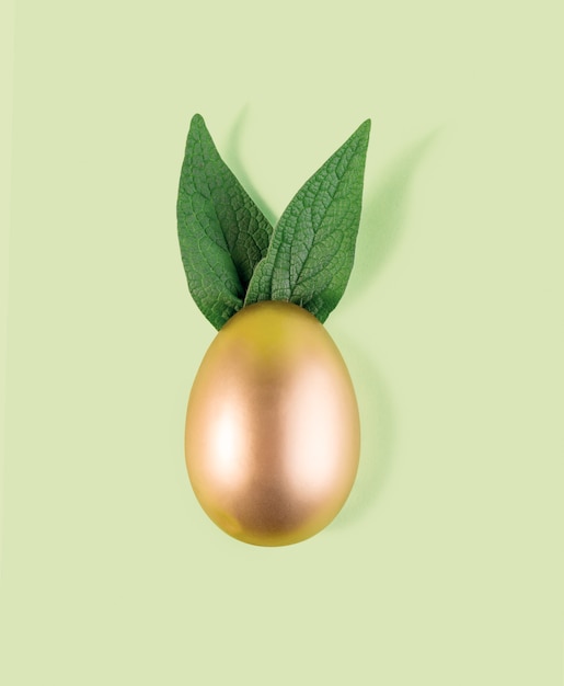 Easter egg painted in gold color with green bunny ears.