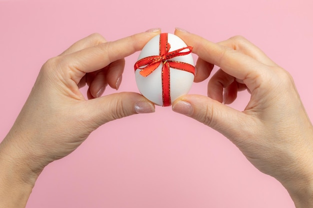 Easter egg with a red ribbon in female hands