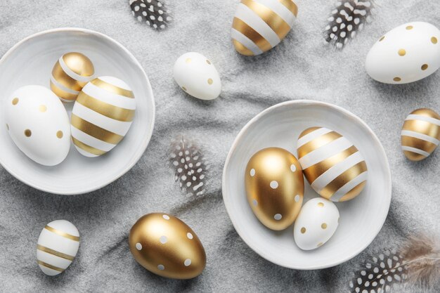 Easter eggs are painted with gold paint on a gray linen background