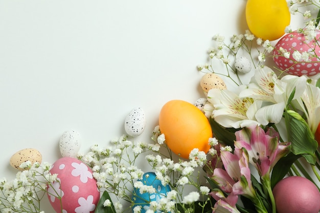 Foto uova di pasqua e bellissimi fiori su sfondo bianco, spazio per il testo