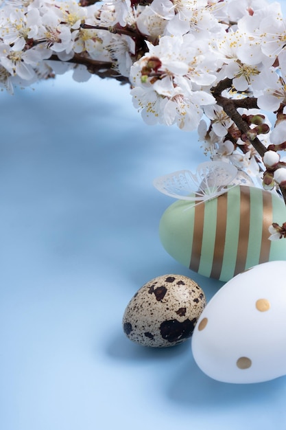 Easter eggs and blossom twig on a blue background with space for text