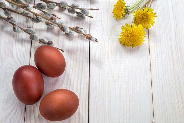 Easter eggs and a bouquet of dandelions on a white table.