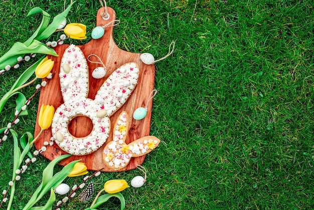 Easter eggs and bunnies on a board on a green grass