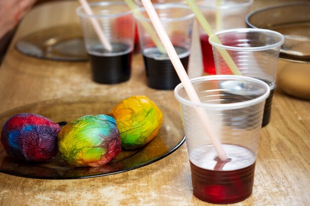 Foto uova di pasqua e vernici liquide colorate sul tavolo