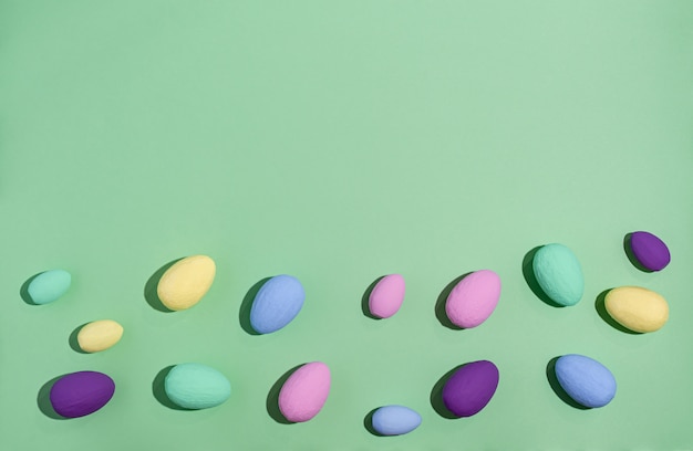 Easter eggs colored with hard shadows on a green background, copy space, flat lay.