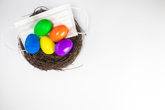 Easter eggs colorful painted in bird nest with protective face mask top view happy easter holiday