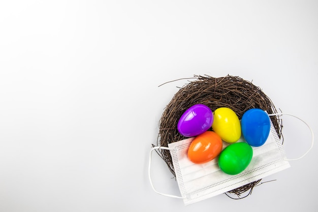 Easter eggs colorful painted in bird nest with protective face mask top view happy easter holiday