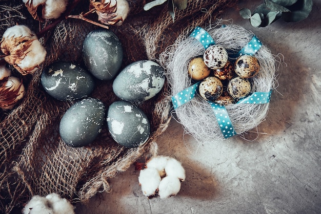 Easter eggs and cotton flowers on grey stone.