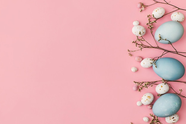 Foto uova di pasqua e fiore piatto giacevano su sfondo rosa con spazio per il testo biglietto d'auguri moderno