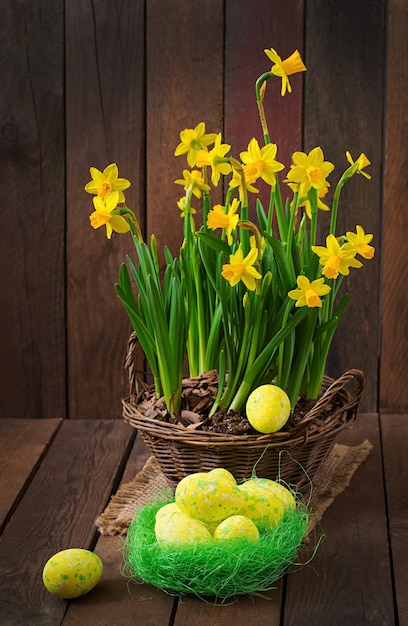 Uova di pasqua e fiori su una tavola di legno scura