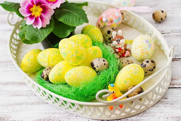 Easter eggs and flowers on a light wooden table