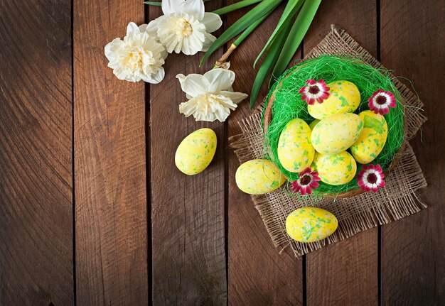 Easter eggs and flowers on wooden background