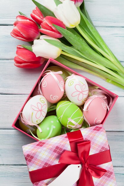 Easter eggs in gift box and colorful tulips