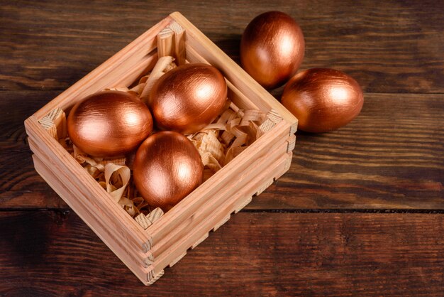 Easter eggs in gift wooden box on dark wooden table. Preparation for the holiday