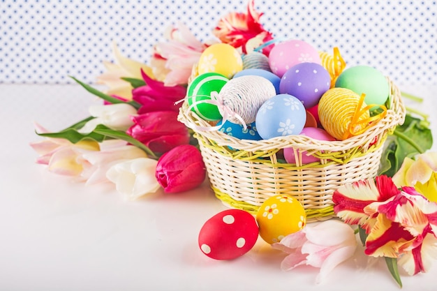 Easter eggs lying in basket and flowers beside