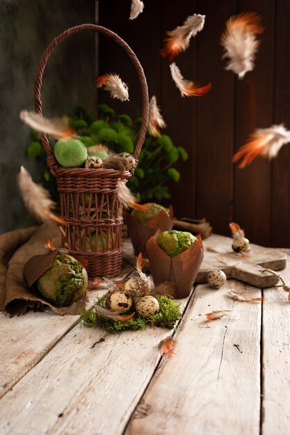 Easter eggs and muffins in a traditional rustic design. Green plants and flying feathers