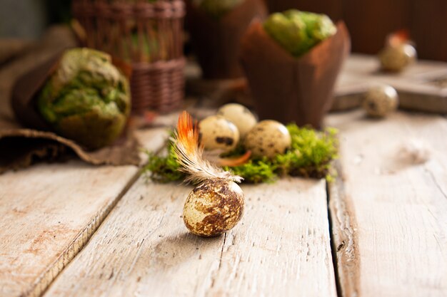 Uova di pasqua e muffin con pistacchio in un design rustico tradizionale. piante verdi e piume