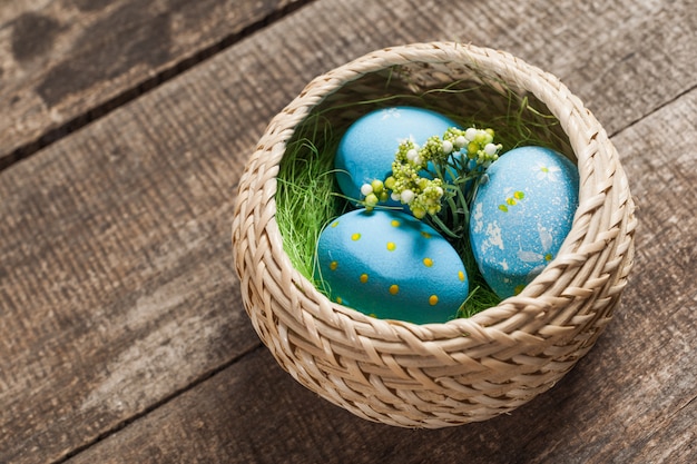 Easter eggs in nest on color wooden background