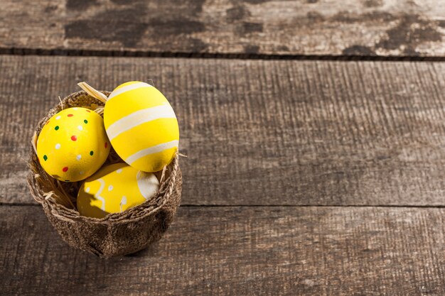 Easter eggs in nest on color wooden 