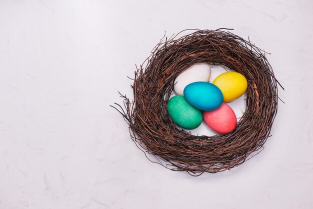 Easter eggs in nest on marble background.