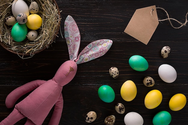 Easter eggs in nest and pink rabbit on a black background